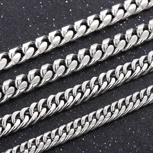 Macro shot of four different widths of silver Cuban link chains on a black textured surface