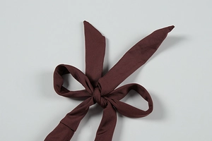 Detailed macro view of adjustable bow tie strap on deep brown high-elasticity fabric