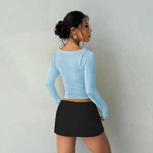 Rear view of light blue lettuce edge long sleeve top paired with a black mini skirt