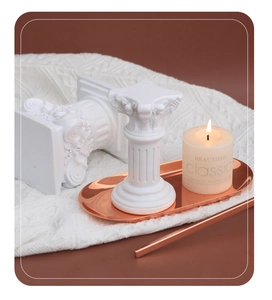 Detail of white resin Roman column decor with scented candle and copper metal tray