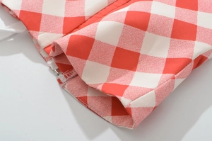 Detail of red and white checkered fabric featuring a zipper and drawstring texture