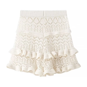 Detailed view of white knitted shorts with intricate lace patterns and ruffled hem edges