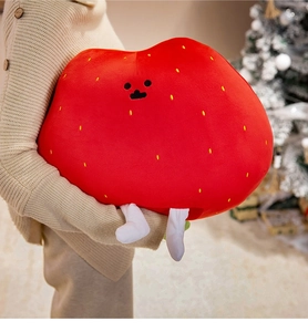 Soft red strawberry plush pillow with cute embroidery held by a model in a cozy setting