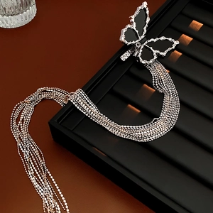 Close-up of silver butterfly earrings with black inlay and long fringe tassel chains