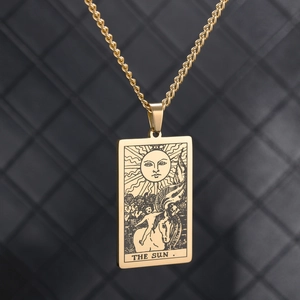 Detailed close-up of The Sun tarot pendant in gold finish over black leather texture