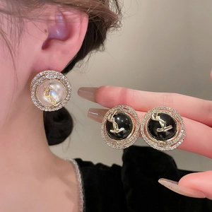 Close-up of elegant YSL logo earrings with faux pearl, black enamel and sparkling crystals