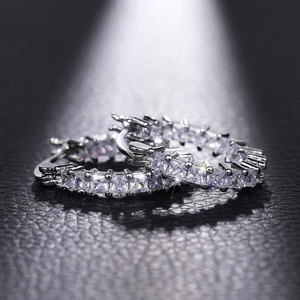 Macro shot of silver-plated hoop earrings with square-cut cubic zirconia on black leather