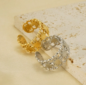 Close-up of hollow flower open rings in gold and silver finish on a stone base
