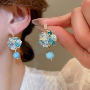 Detail of floral drop earrings with blue beads and mint green crystal petals