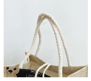 Detail of white cotton rope handle and bear print on a burlap lunch tote bag