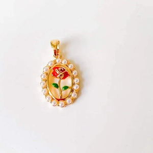 Detail of oval gold necklace pendant with red enamel rose and pearl border