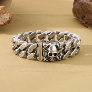 Detail of vintage silver skull cuban link bracelet with embossed clasp on wood