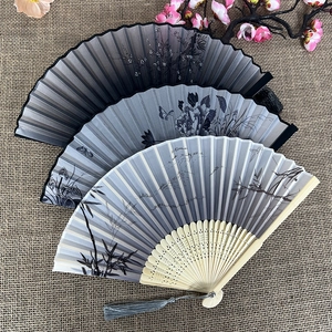 Three Chinese folding fans with bamboo ribs and ink painting designs on linen background