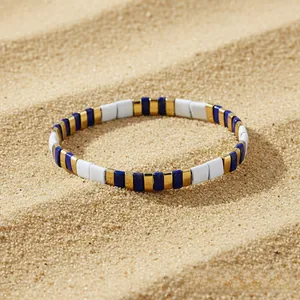 Detail view of blue and white beaded bracelet on beach sand with summer holiday vibe