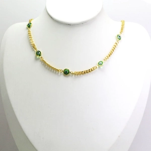 Close-up of golden necklace with green evil eye beads on a neck mannequin