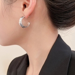 Close-up of chunky silver hoop earring with fluid liquid metal texture on model ear
