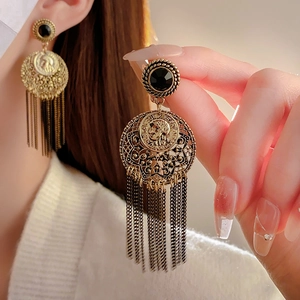 Detail of vintage gold tassel earrings featuring a round portrait coin and black stone