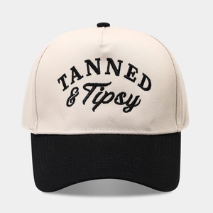 Detailed embroidery of TANNED & Tipsy text on a contrast baseball cap with high texture