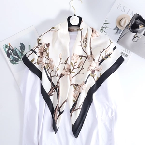 Detail of elegant ivory silk square scarf with magnolia flower print and black borders