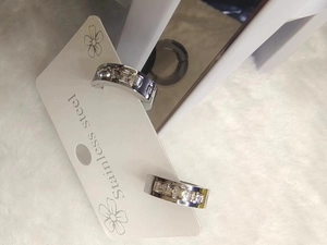 Detailed macro view of silver stainless steel hoop earrings with sparkling square zircons