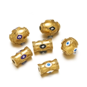 Macro detail of gold evil eye charms in cylindrical and oval shapes for DIY jewelry