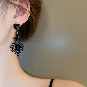 Detail of vintage black heart drop earrings with rhinestone accents on model's ear