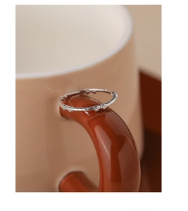 Macro shot of S925 sterling silver bow knot ring placed on a brown coffee cup handle