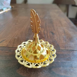 Detail of golden incense burner featuring an intricate hollow base and feather handle