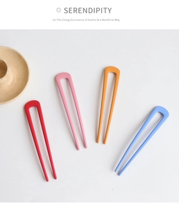 Close-up of four matte U-shaped hairpins in red, pink, yellow, and blue colors