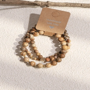 Detailed macro view of three handmade natural stone beaded bracelets with heart pendant