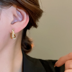 Detail of vintage gold hoop earring with zircon and pearls worn on an earlobe