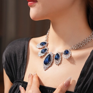Detailed close-up of layered necklace with blue sapphires and diamonds on a model