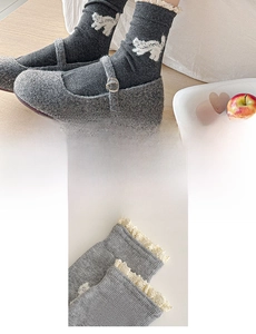 Detailed close-up of grey mid-calf socks with cute white cat patterns and cream lace trim