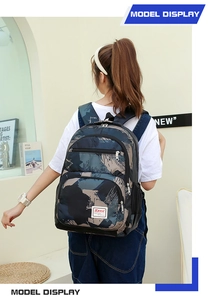 Rear view of model wearing a dark camo backpack with multiple compartments and side pockets