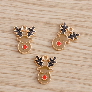 Detail of cute enamel Christmas reindeer charms with gold alloy edges on wood surface