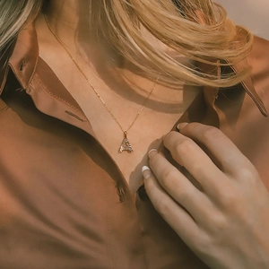 Fashionable gold stainless steel initial A letter necklace worn by model on brown shirt
