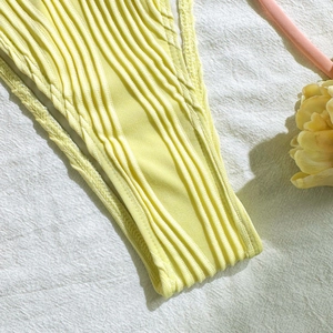 Detail of bright yellow ribbed swimwear fabric featuring elastic texture and soft lighting