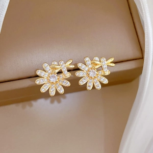 Macro shot of gold floral earrings with clear zircon stones on a luxury jewelry box