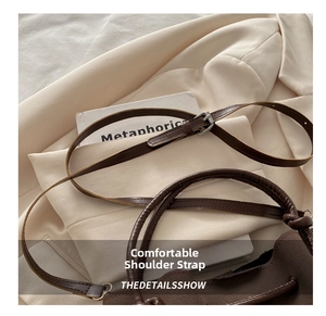 Detail of adjustable brown leather shoulder strap with silver buckle on a bucket bag
