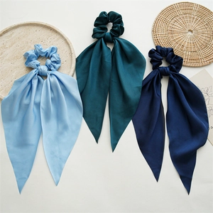 Detailed view of three satin scarf scrunchies in blue, forest green and navy blue silk fabric