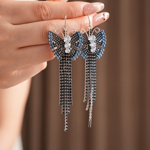 Dettaglio orecchini vintage a farfalla con zirconi blu e lunghe nappe metalliche