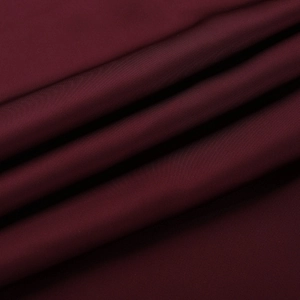Close-up of deep red satin fabric with elegant twill texture and smooth glossy finish