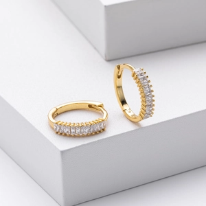 Macro detail of gold hoop earrings featuring square-cut cubic zirconia inlays