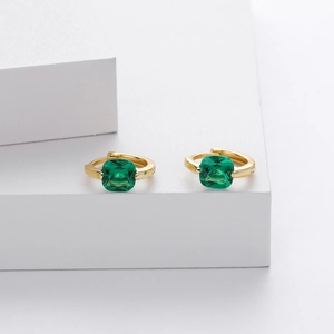 Detailed view of gold hoop earrings with green square-cut cubic zirconia gemstones