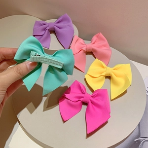 Detail view of colorful bow hair clips set with matte fabric and metal duckbill clip