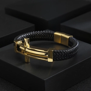 Detail of black braided leather men's bracelet with golden steel cross and clasp