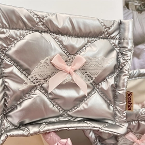Detail of silver quilted storage box with pink lace bow and side brand woven label