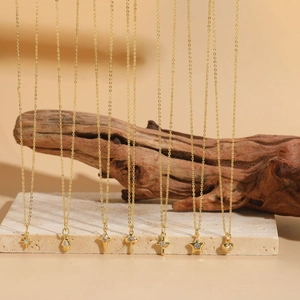Close-up of gold-plated necklaces with dainty star and heart zircon pendants on a stone base