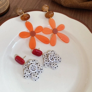 Detail view of vintage resin flower tassel earrings on white porcelain tray background