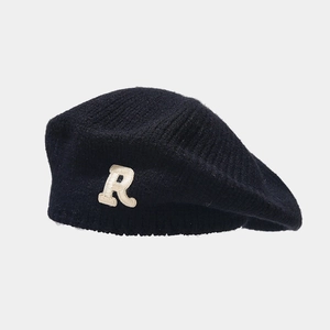Close-up of black knitted beret with white boucle embroidery R letter detail
